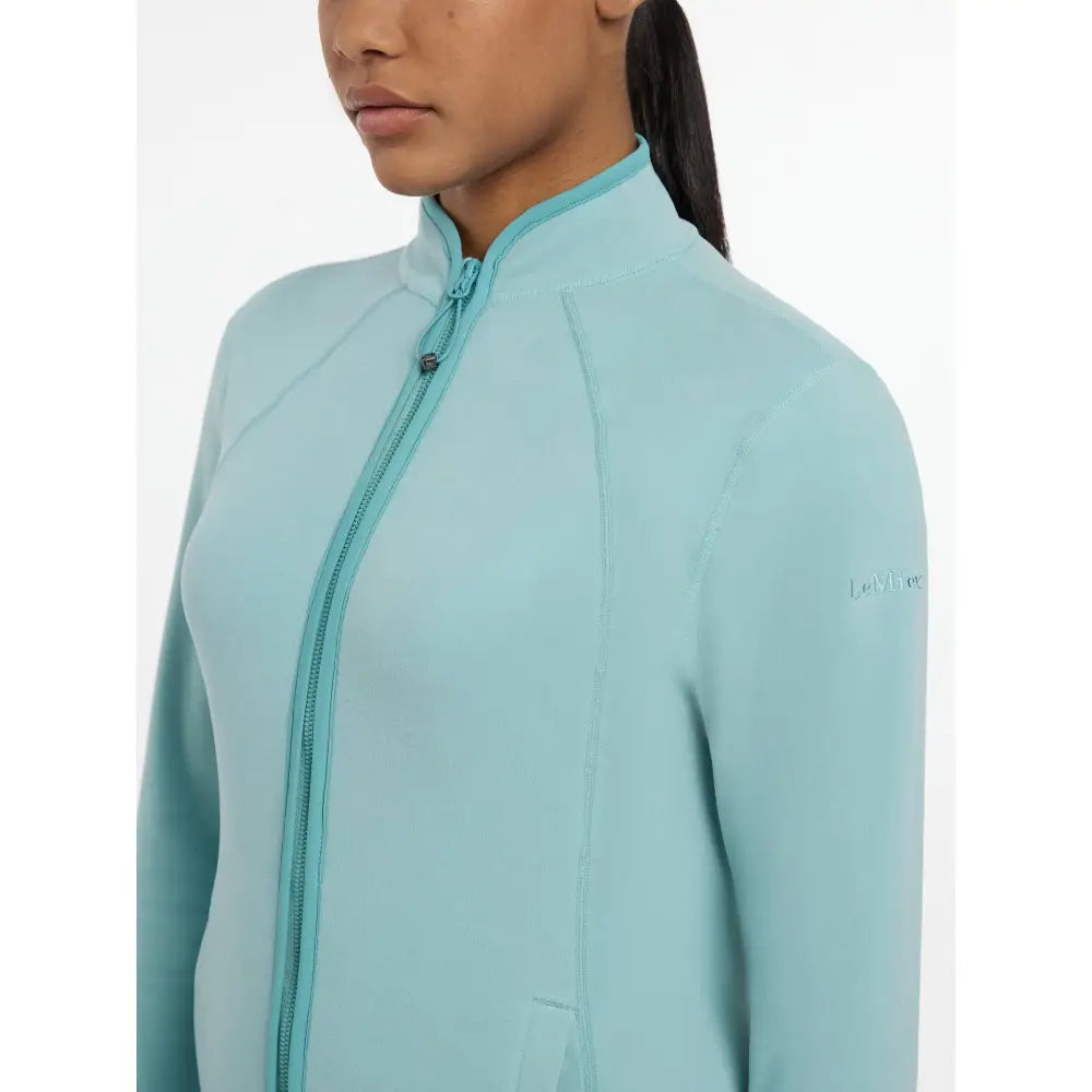 A light blue lemieux faye fleece zip soft shell jacket with a subtle logo on the sleeve for cozy wear