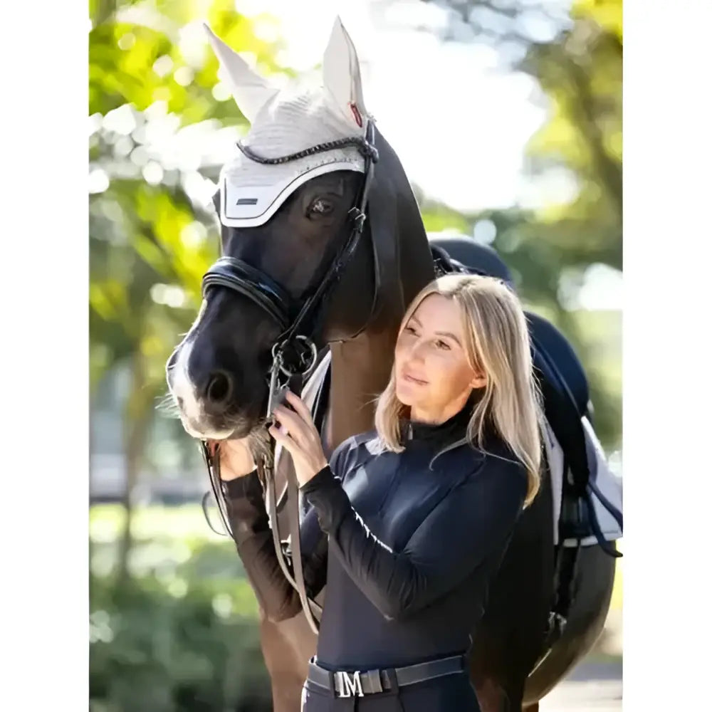 Black horse wearing a white mesh lemieux finesse acoustic fly hood stone for fly protection and noise reduction
