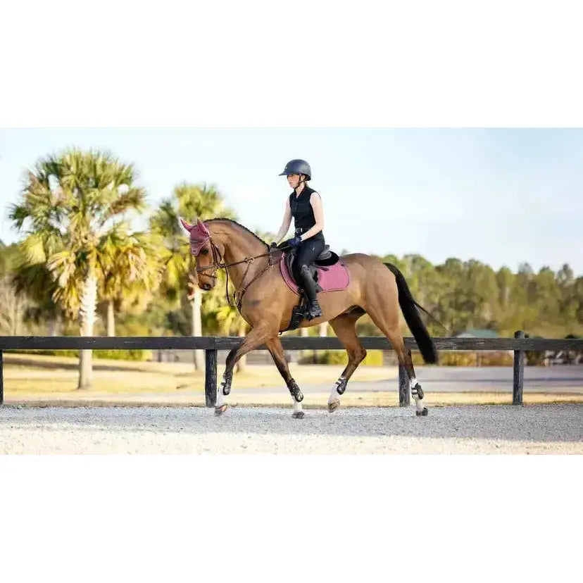 A chestnut horse wearing a lemieux finesse eurojump saddle pad in rosewood pink with matching fly mask and black gear