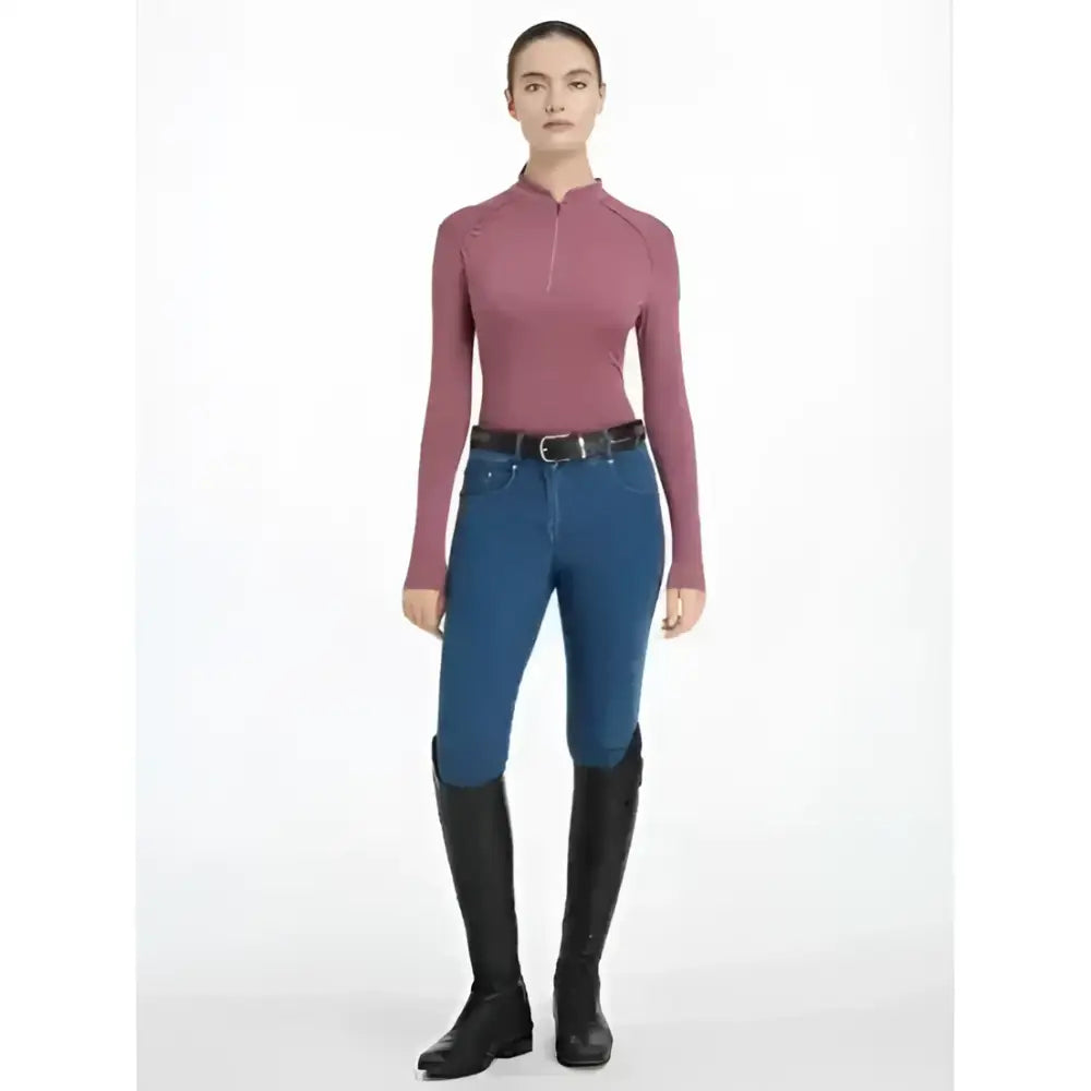 A woman wears a fitted long-sleeved maroon lemieux heyden lightweight base layer rosewood zip neck top with seams