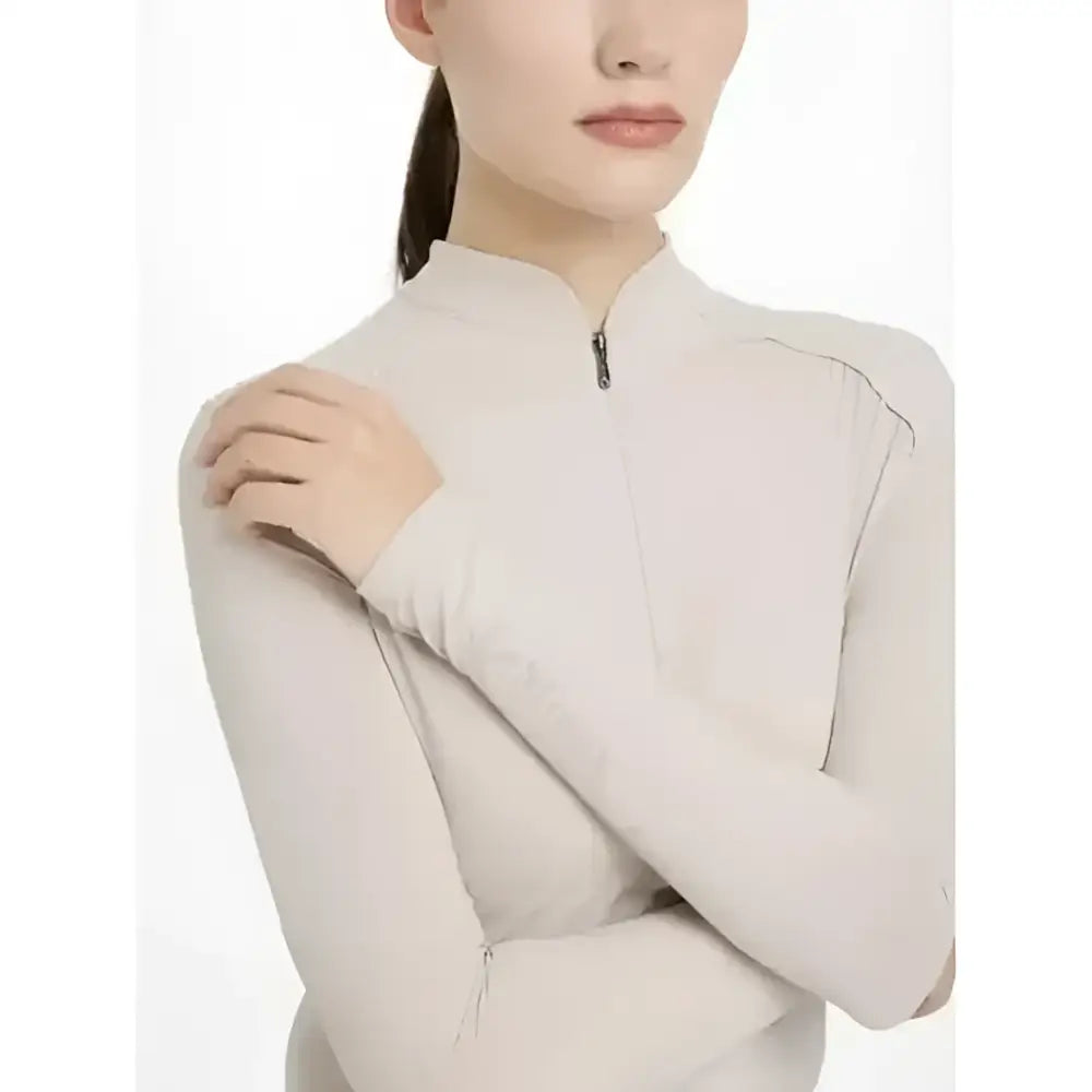 A sleek off-white lemieux heyden lightweight base layer stone long sleeve top with high collar and zipper detail