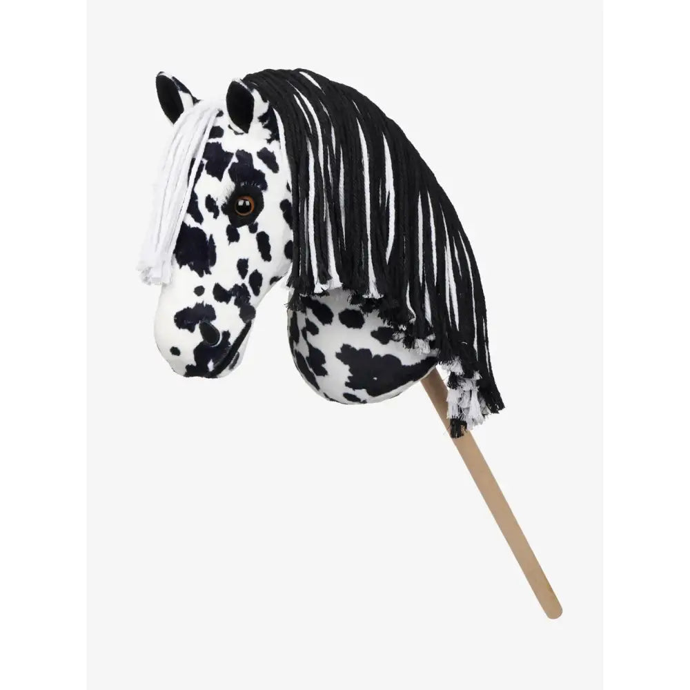 A plush black and white spotted lemieux hobby horse dakota with a flowing mane on a wooden stick for mini riders