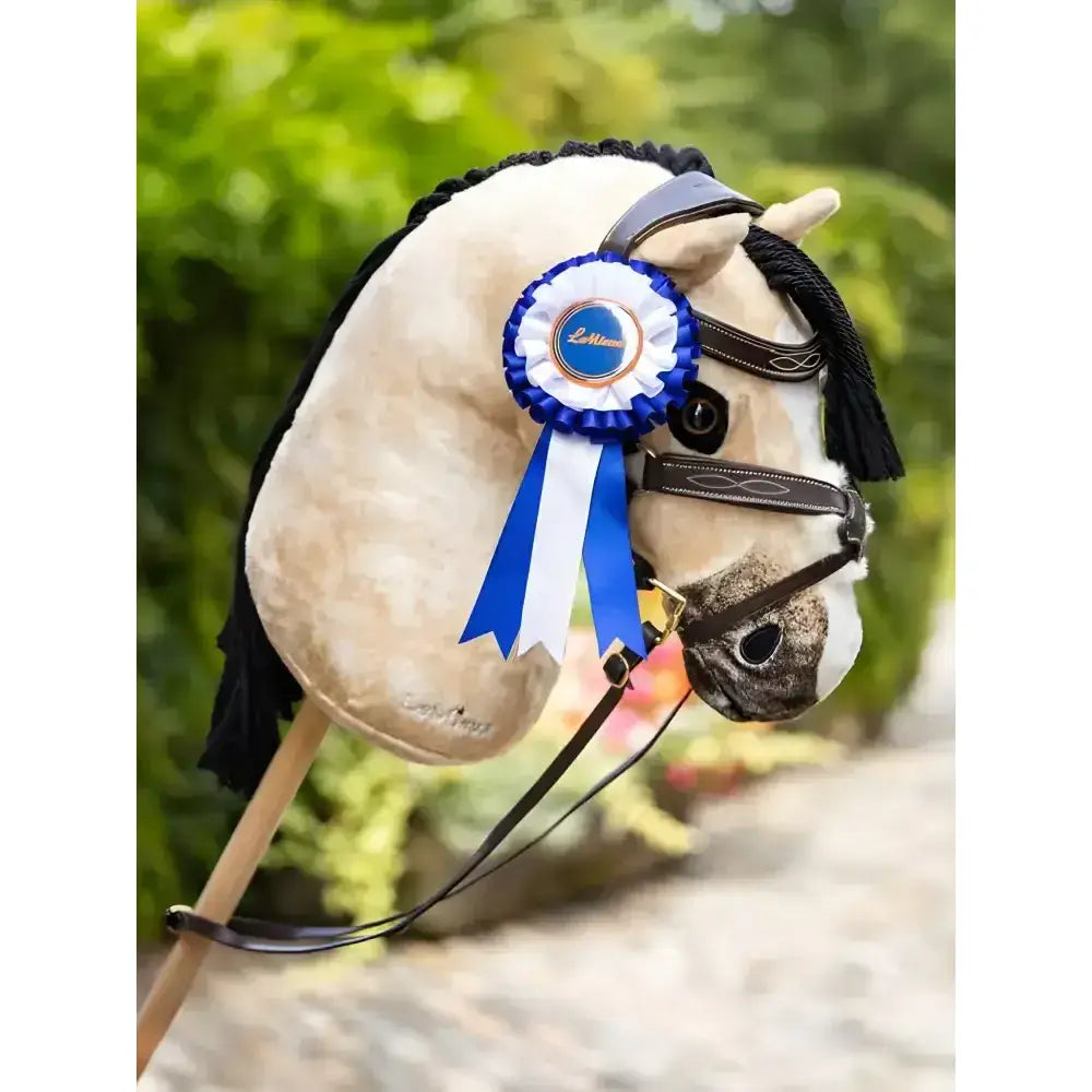 A plush cream lemieux hobby horse with black braided mane and hobby horse rosette featuring winner’s rosettes