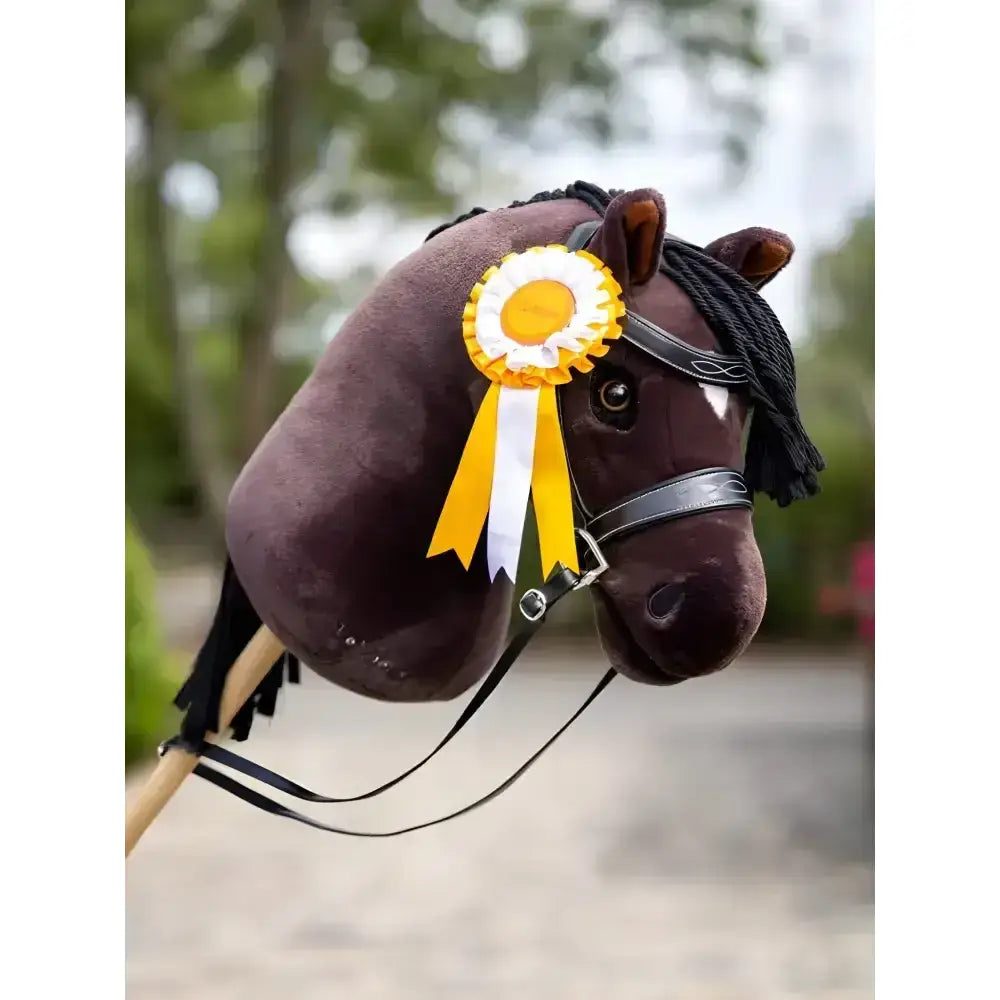 A plush dark brown lemieux hobby horse head with black bridle and yellow white hobby horse rosette winner’s rosettes