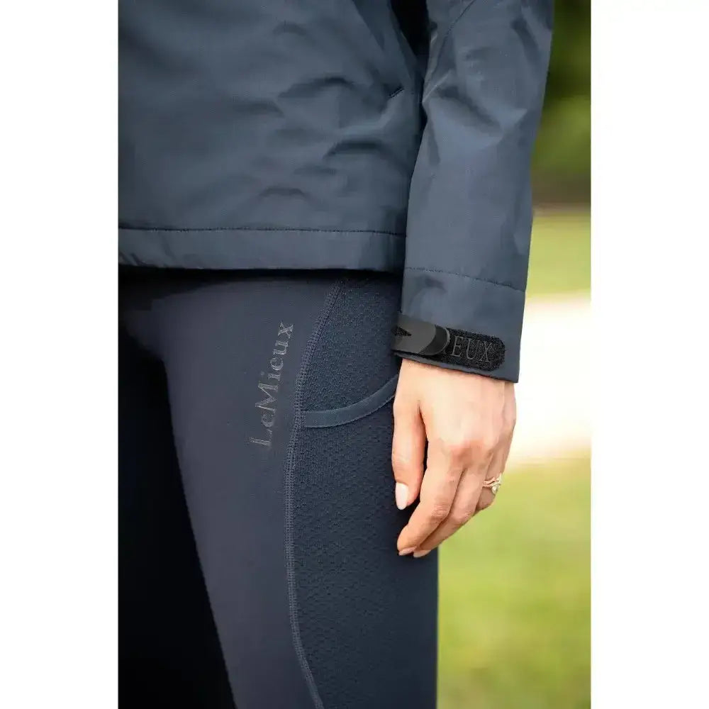 Dark gray form-fitting equestrian leggings with lemieux logo and black cuff paired with lemieux isla short waterproof jacket navy