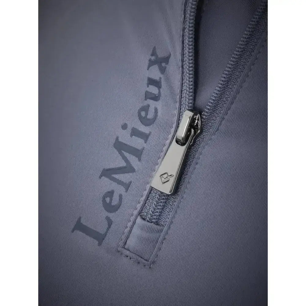 Silver zipper pull with small logo on gray fabric of lemieux ladies base layer jay blue top