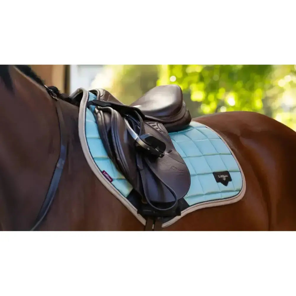 Light blue quilted lemieux loire classic saddle pad with white trim and black logo for classic close contact riding