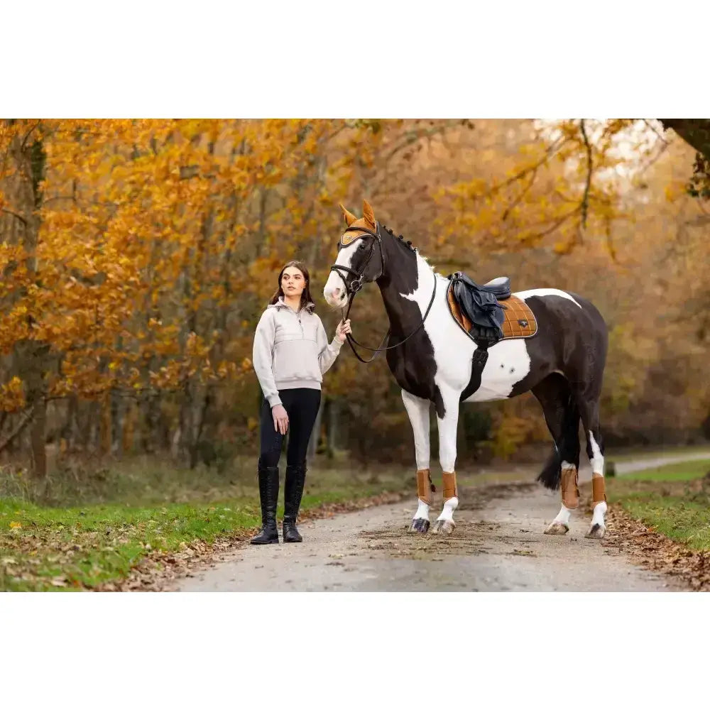 A black and white pinto horse stands on a dirt path showcasing lemieux loire classic close contact saddle in autumn