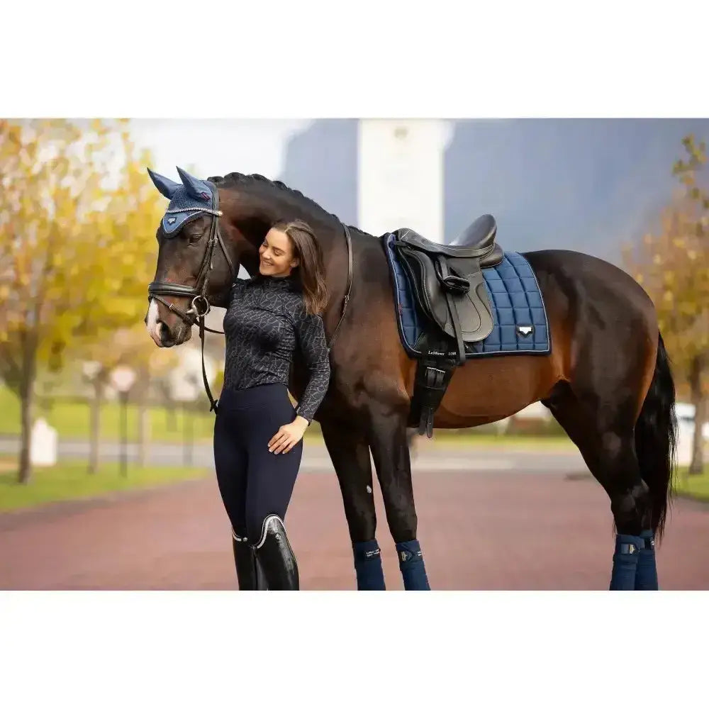 Dark brown horse wearing lemieux loire classic navy blue stylish dressage pad and ear bonnet in woven satin fabric