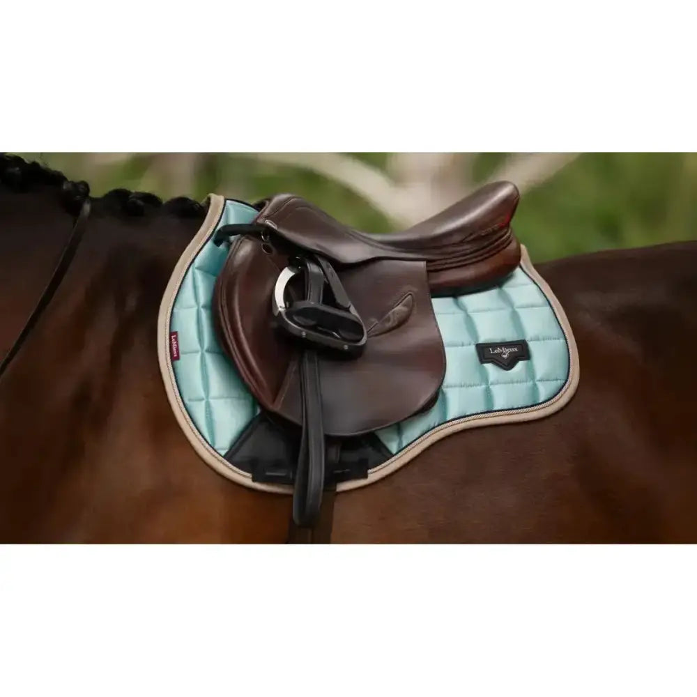 Light blue quilted lemieux loire classic gp square saddle pad with beige trim and brown leather saddle on top