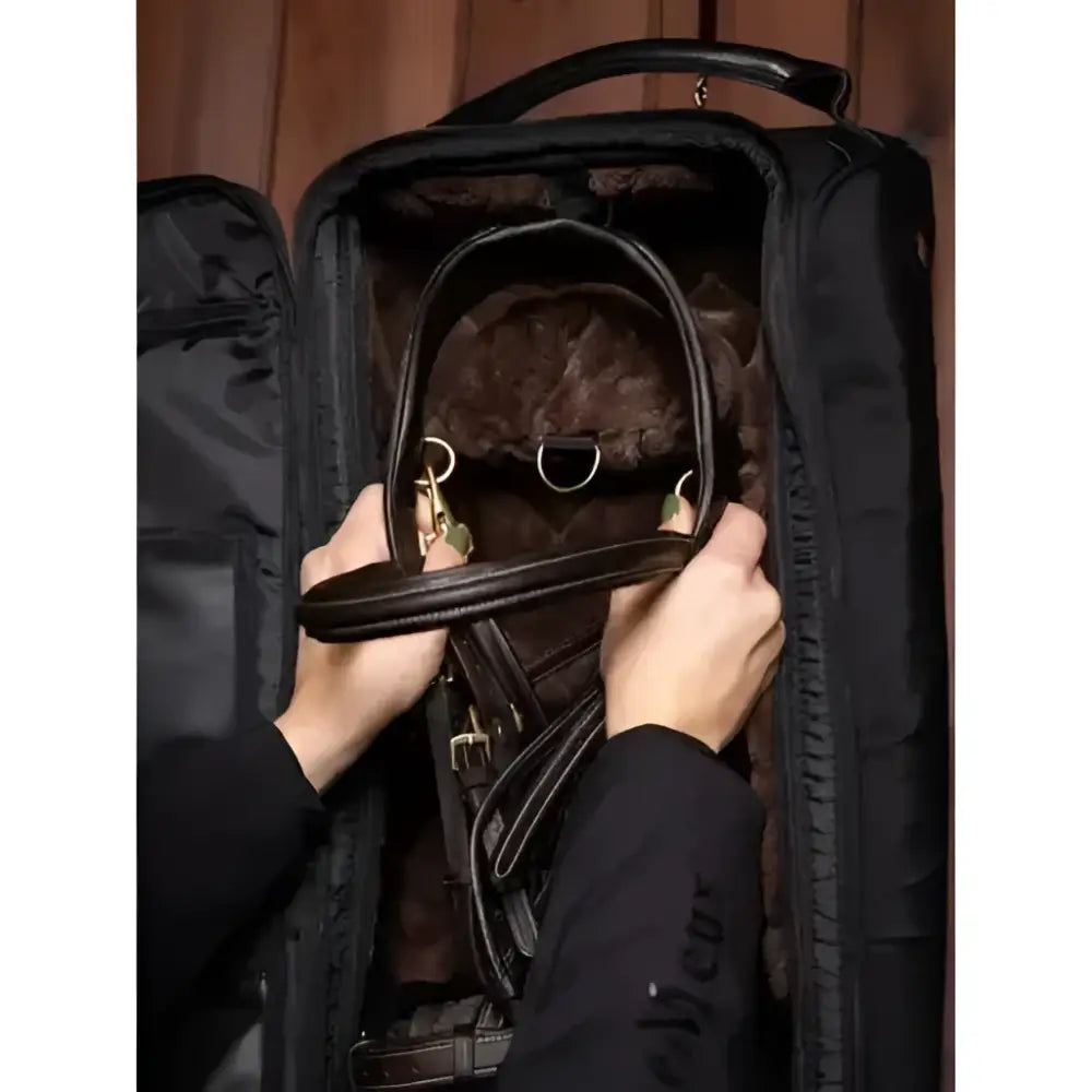 Brown leather horse bridle with gold metal hardware displayed with lemieux luxe bridle black faux leather bag