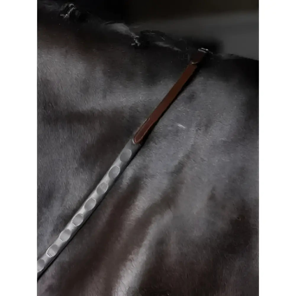 Silver metal riding crop with textured oval handle and brown leather strap paired with lemieux magna grip rubber reins havana brass