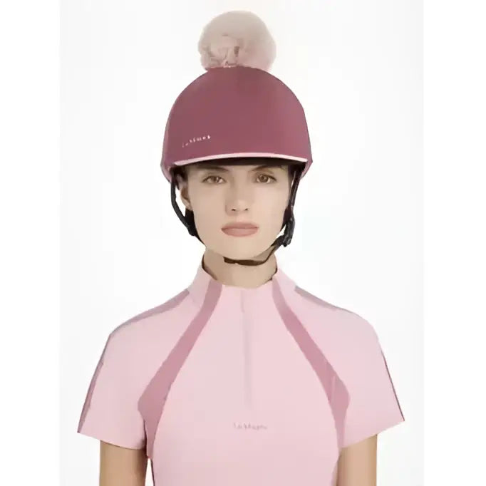 A maroon lemieux maria mesh equestrian helmet with a fluffy pink pom-pom in silk rosewood color