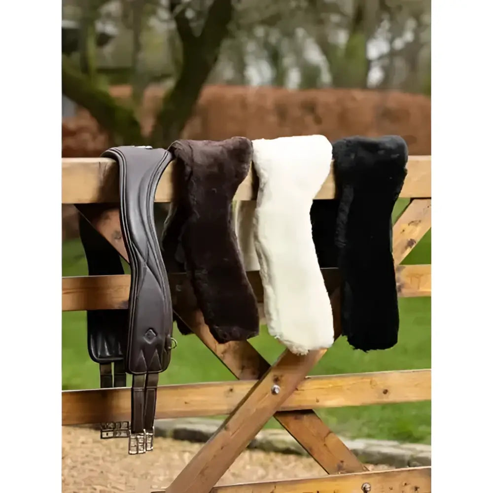 Four leather and faux fur saddle pads in brown black cream and dark chocolate shown with anatomic jumping girth cover black