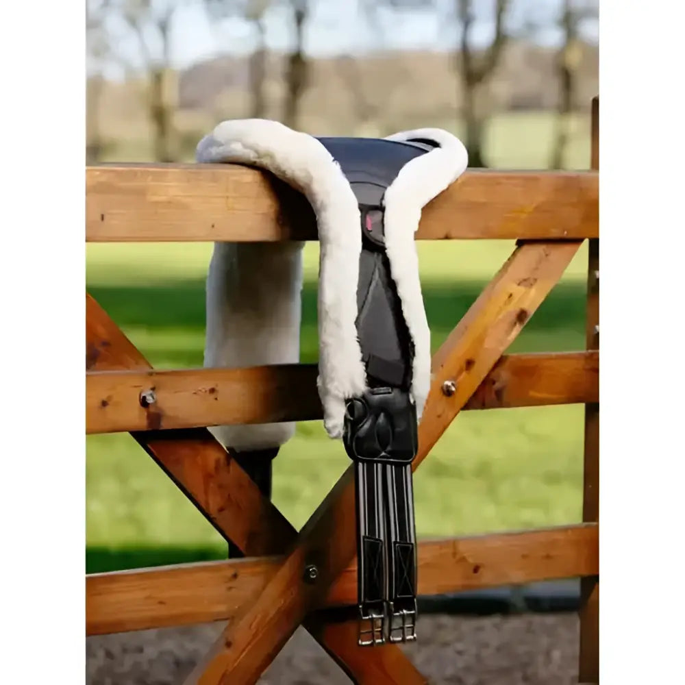 Black leather horse saddle with white fleece lining paired with LeMieux merino anatomic long stud girth cover natural