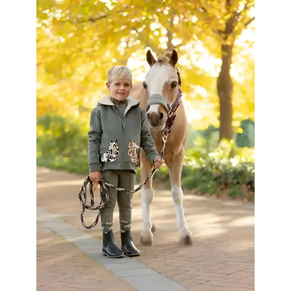 A young child wearing a grey lemieux mini charlie pony hoodie rosemary with white fur hood and floral patches