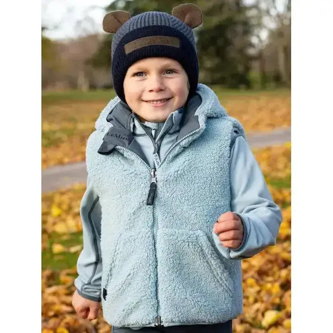 Light blue fleece-lined lemieux mini elsie reversible gilet petrol with gray zipper and hood worn over matching jacket