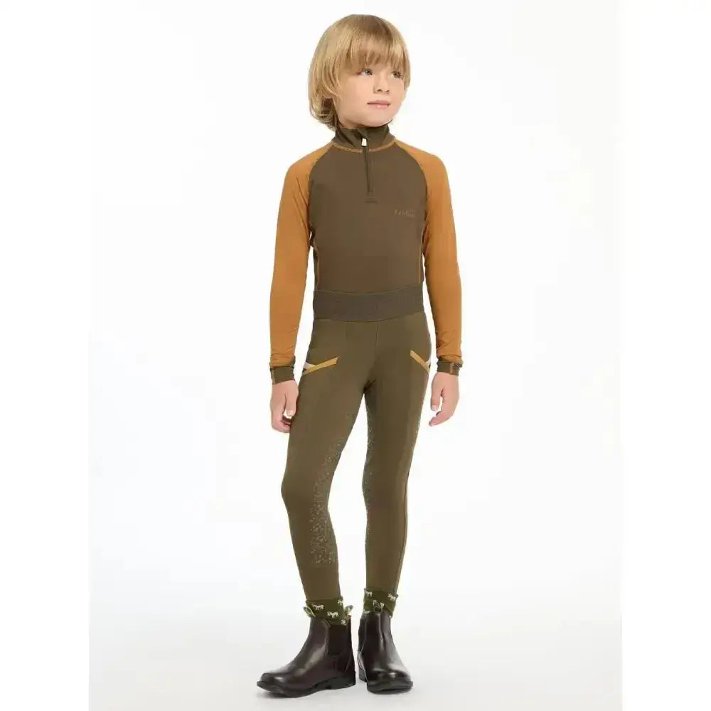 A child wearing lemieux mini pull ons alpine in olive green and mustard yellow with black riding boots