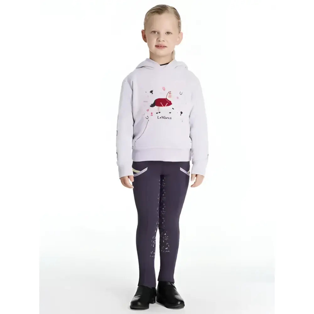 A child wears a lemieux mini romi hoodie lilac with a red black graphic and dark purple patterned leggings