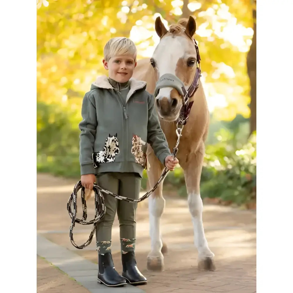 A young boy in a green fleece stands beside a horse wearing the lemieux mini vogue headcollar and leadrope damson