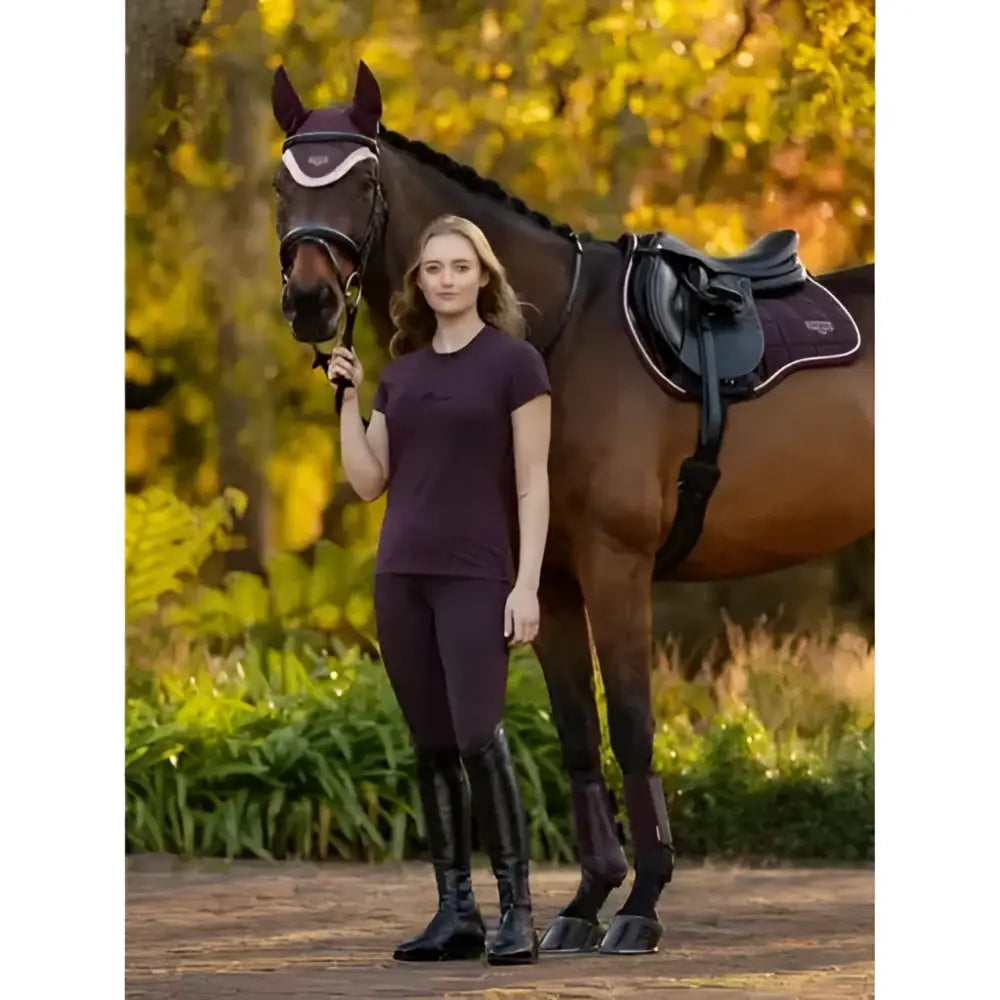 Woman wearing lemieux naomi pull damson breeches with dark purple equestrian top and black riding boots