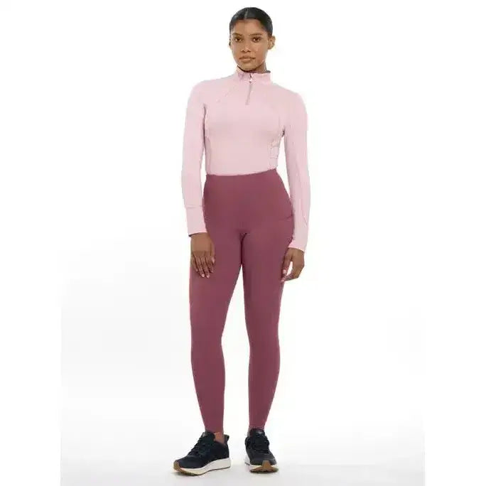 A woman wearing lemieux naomi pull rosewood long-sleeved quarter-zip top and matching pull on breeches