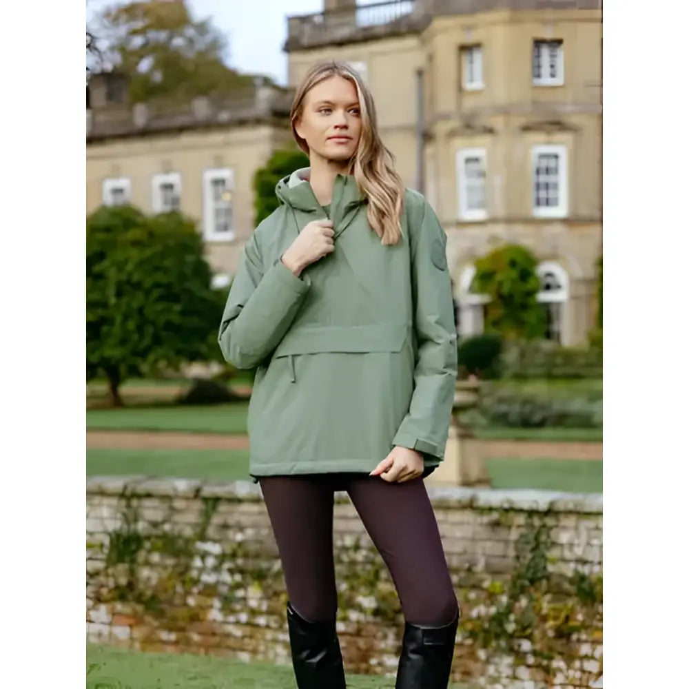 A woman wearing a sage green lemieux phoebe half zip waterproof anorak rosemary quilted puffer jacket with hood and pocket