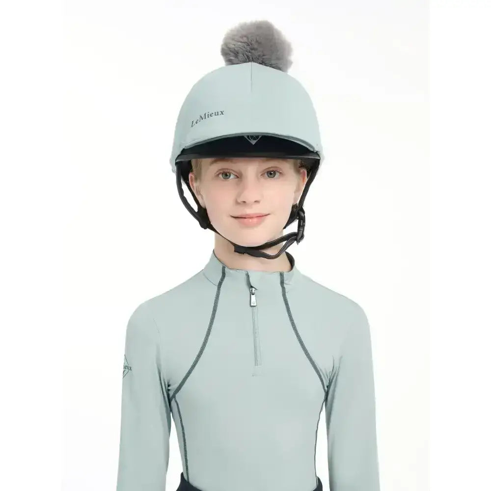 Light blue lemieux pippa hat silk equestrian helmet with gray faux fur pom-pom and silky smooth four-way fabric