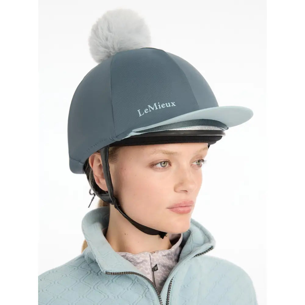A sleek slate-gray lemieux pom hat with a soft white pom-pom made from silky smooth four-way hat silk petrol fabric