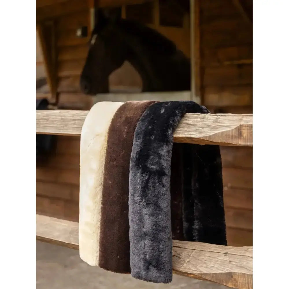 Three lemieux simuwool breastgirth covers in cream brown and black with soft high density fabric hanging on a fence