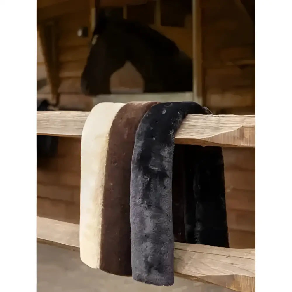 Three lemieux simuwool breastgirth covers in cream brown and black made of high density simuwool draped over a wooden fence