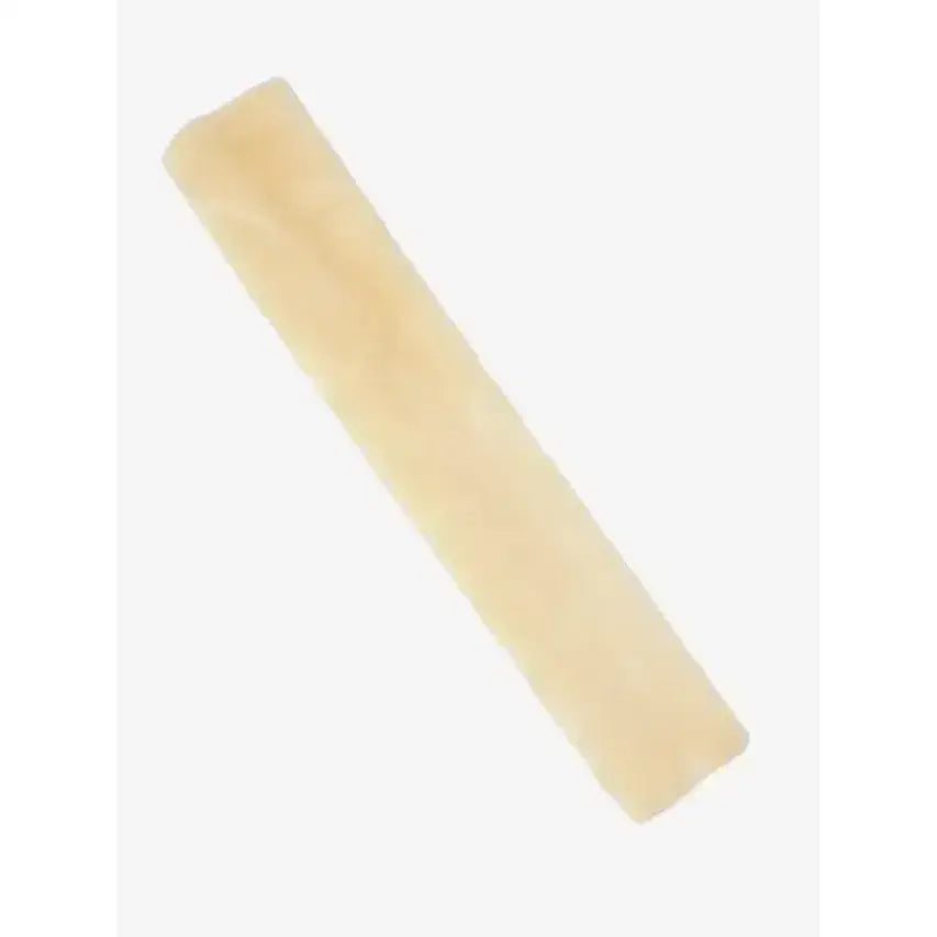 Pale yellow rectangular block of cheese with textured surface shown next to lemieux simuwool gp slip cushioned faux lambswool girth sleeve natural