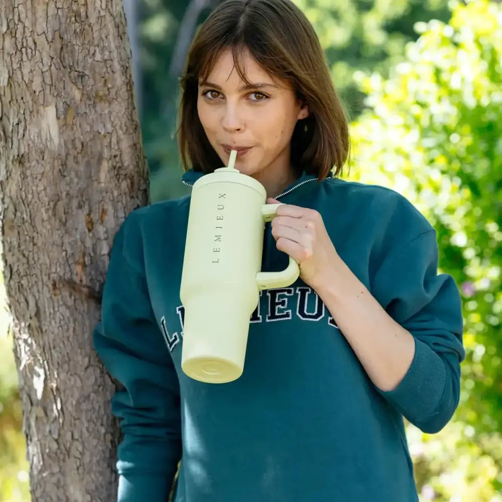 A pale green cylindrical insulated lemieux sports cup macaron with handle and brand name printed vertically