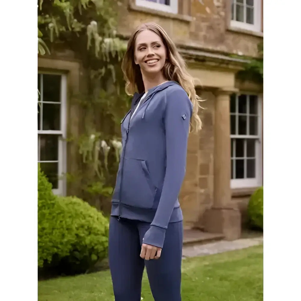 A woman wearing a lemieux tabi tech hoodie dusk blue with long sleeves and a front pocket featuring a tech zip