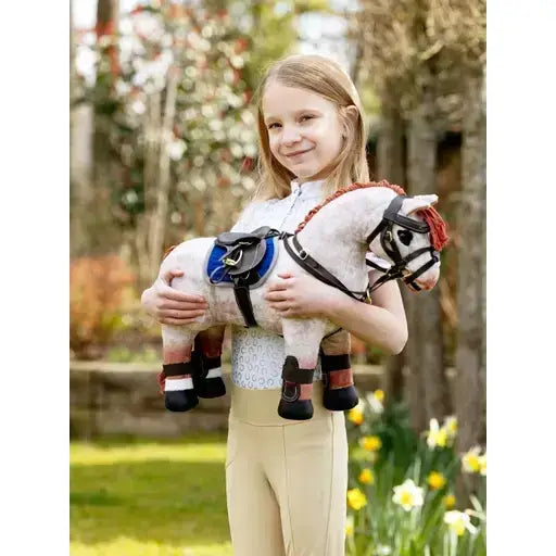 A plush white lemieux toy pony with black and red harness and blue saddle accents wearing capella boots brown