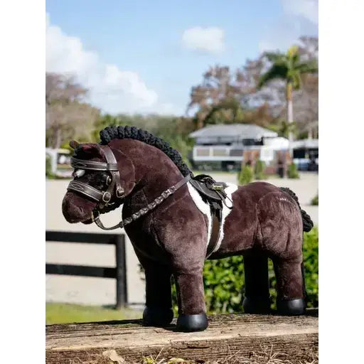 A plush brown lemieux toy pony with a black braided mane wearing a detailed pony hunter saddle and hunter saddle pad