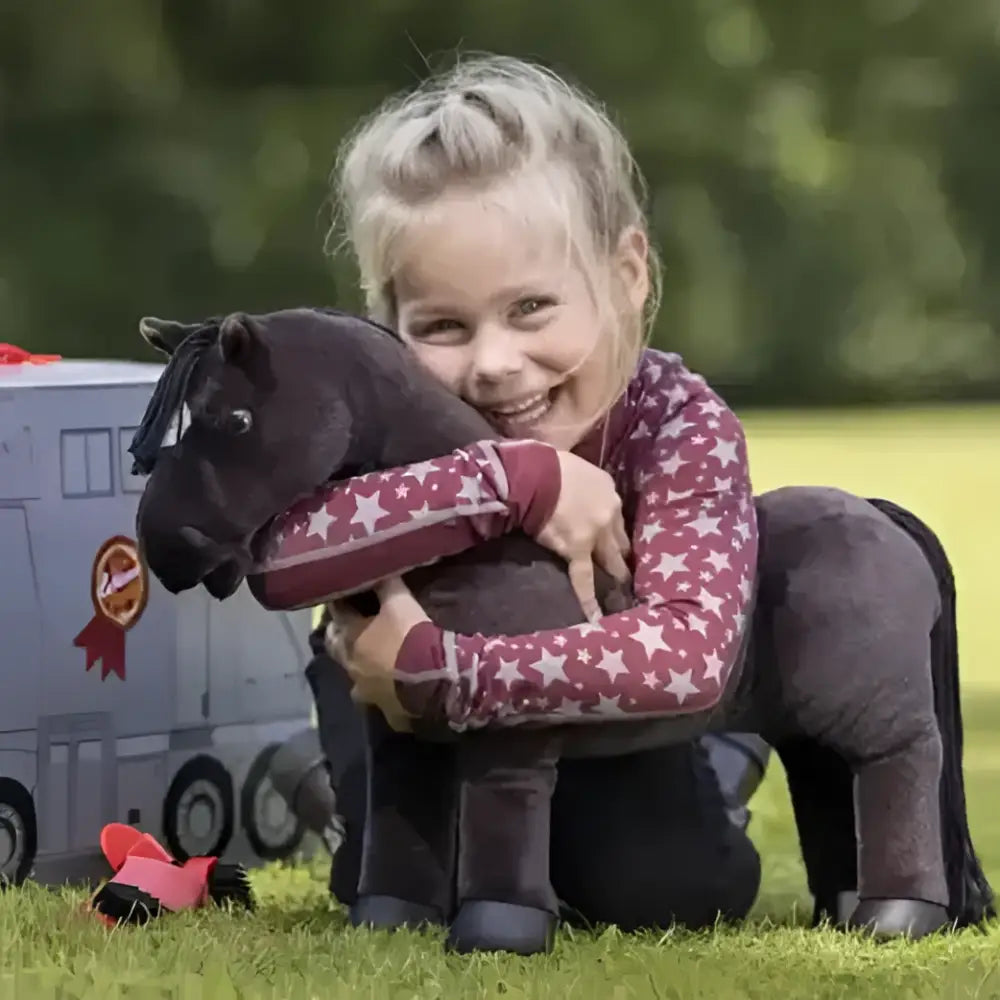 A plush black lemieux toy pony with soft velvety texture and stitched details in a pony reversible carry case