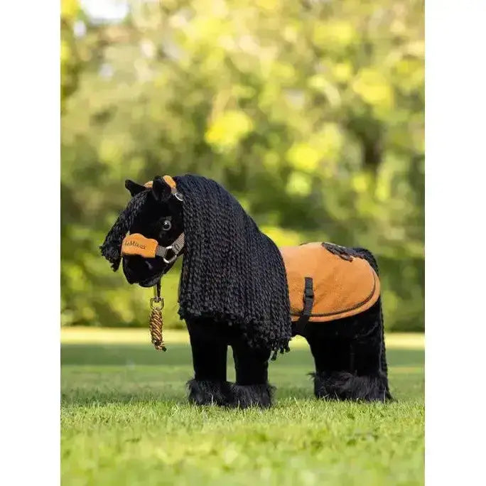 Black plush lemieux toy pony spike with knitted black mane and orange saddle near stable door background