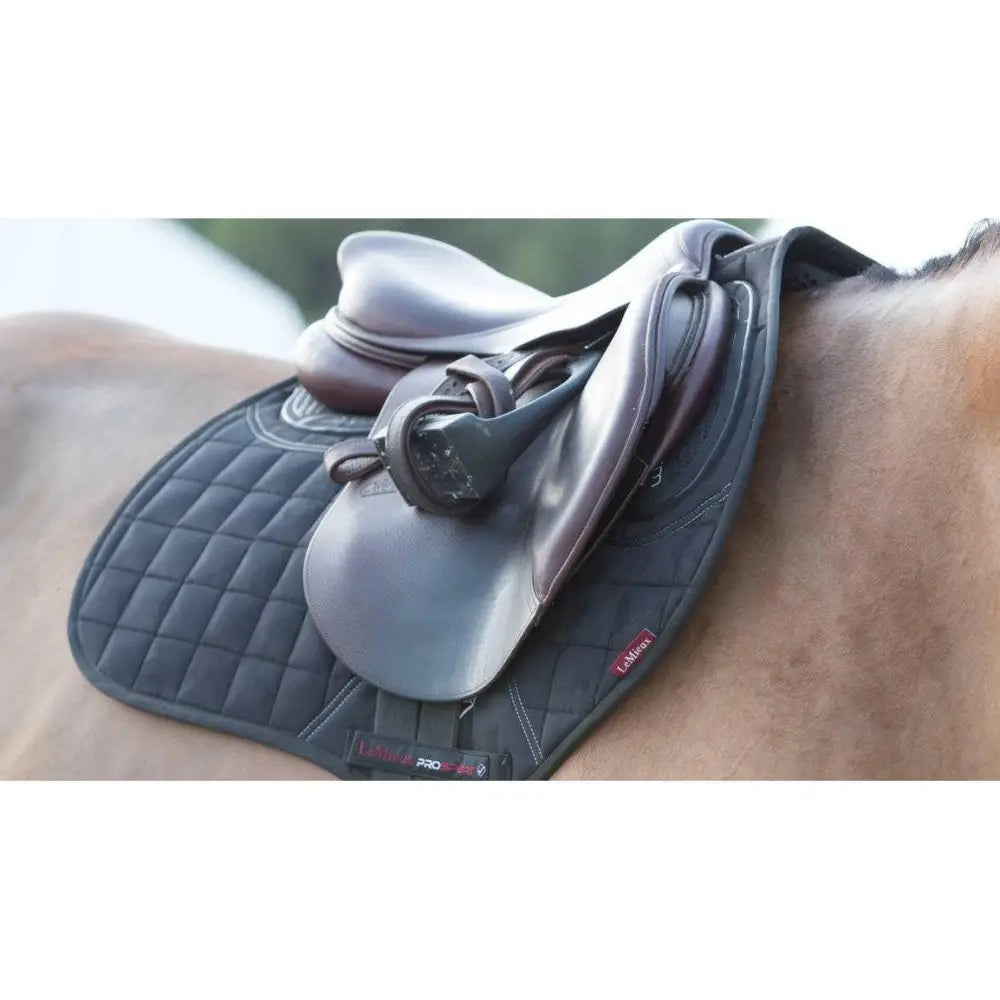 Black quilted twin sided eurojump saddle pad with subtle red logo and x-grip silicone, paired with brown leather saddle