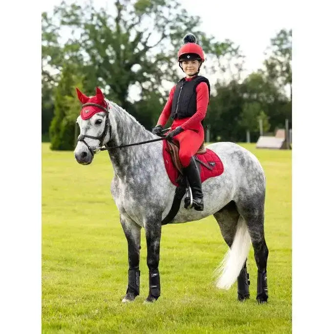 A lemieux young rider in a red rider base layer chilli outfit sits on a dapple grey horse with matching red gear