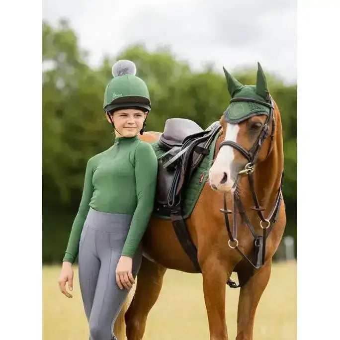 Green riding helmet with fluffy pom pom on top from lemieux young rider base layer hunter green collection
