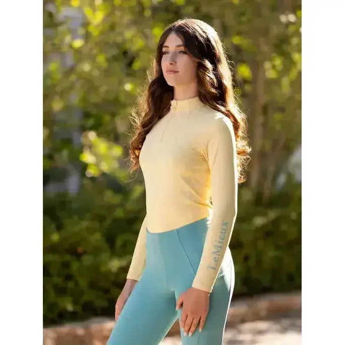 A pale yellow lemieux young rider base layer mimosa with long sleeves high collar and subtle sleeve branding