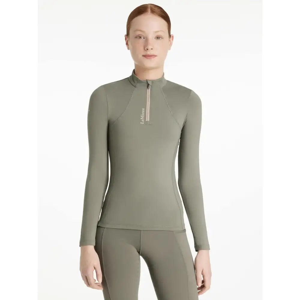 A sleek olive green lemieux young rider rosemary base layer with long sleeves high collar and zipper detail
