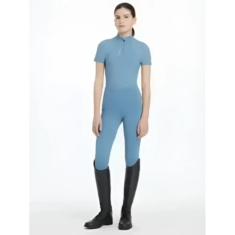 A light blue lemieux young rider classic short sleeve equestrian jumpsuit with high collar and form-fitting design