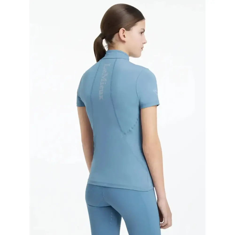 A light blue lemieux young rider classic short sleeve ice layer base layer with a high collar and form-fitting design