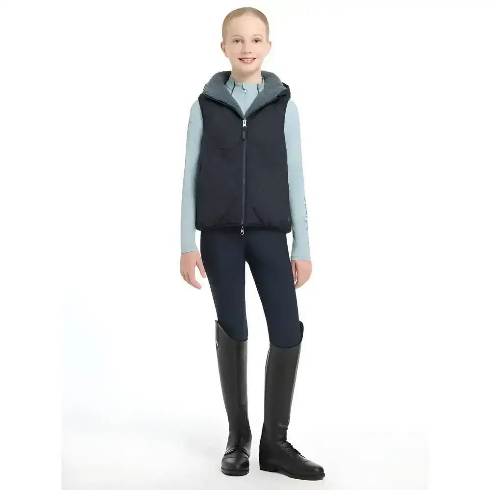 Black zip-up vest with gray hood lining worn over light blue shirt from lemieux young rider eloise reversible gilet navy