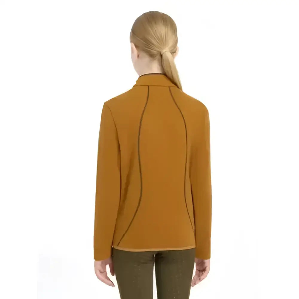 A woman wearing a mustard yellow lemieux young rider felicity fleece zip long sleeve jacket with black stitching