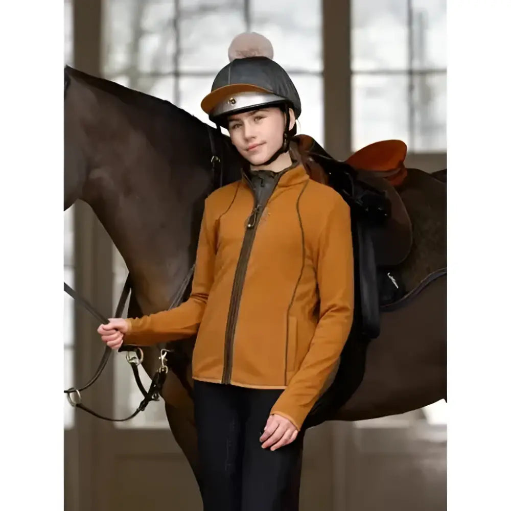A woman wearing an orange lemieux young rider felicity fleece zip long sleeve riding jacket with black zipper accents