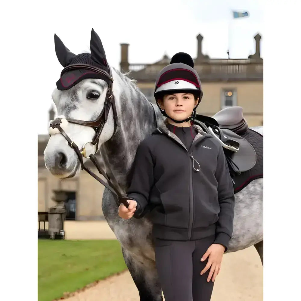 Black equestrian helmet with white stripe and red band paired with lemieux young rider hollie lined hoodie cinder