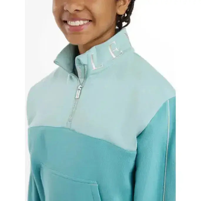 A lemieux young rider kate quarter zip fleece jacket in light blue and teal with silver zippers and chest embroidery